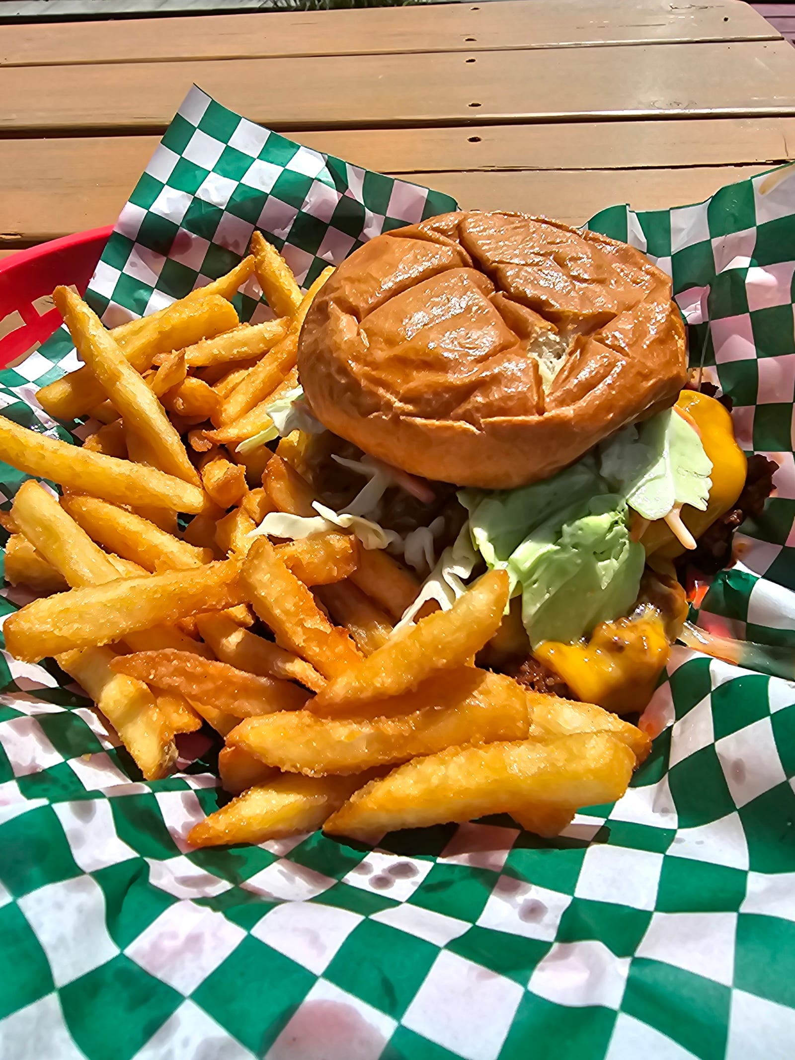 A Lu Lou's Deluxe Sloppy Joe on a toasted brioche bun with melted cheddar and crisp lettuce, served in a checker-lined basket with fries