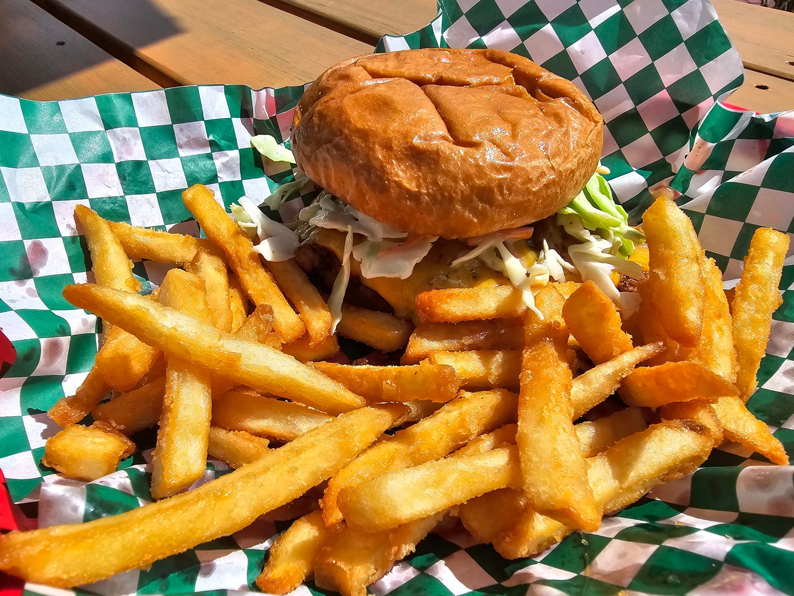 A Lu Lou's Sloppy Joe on a toasted brioche bun, piled with house slaw, served in a checker-lined basket with a side of fries