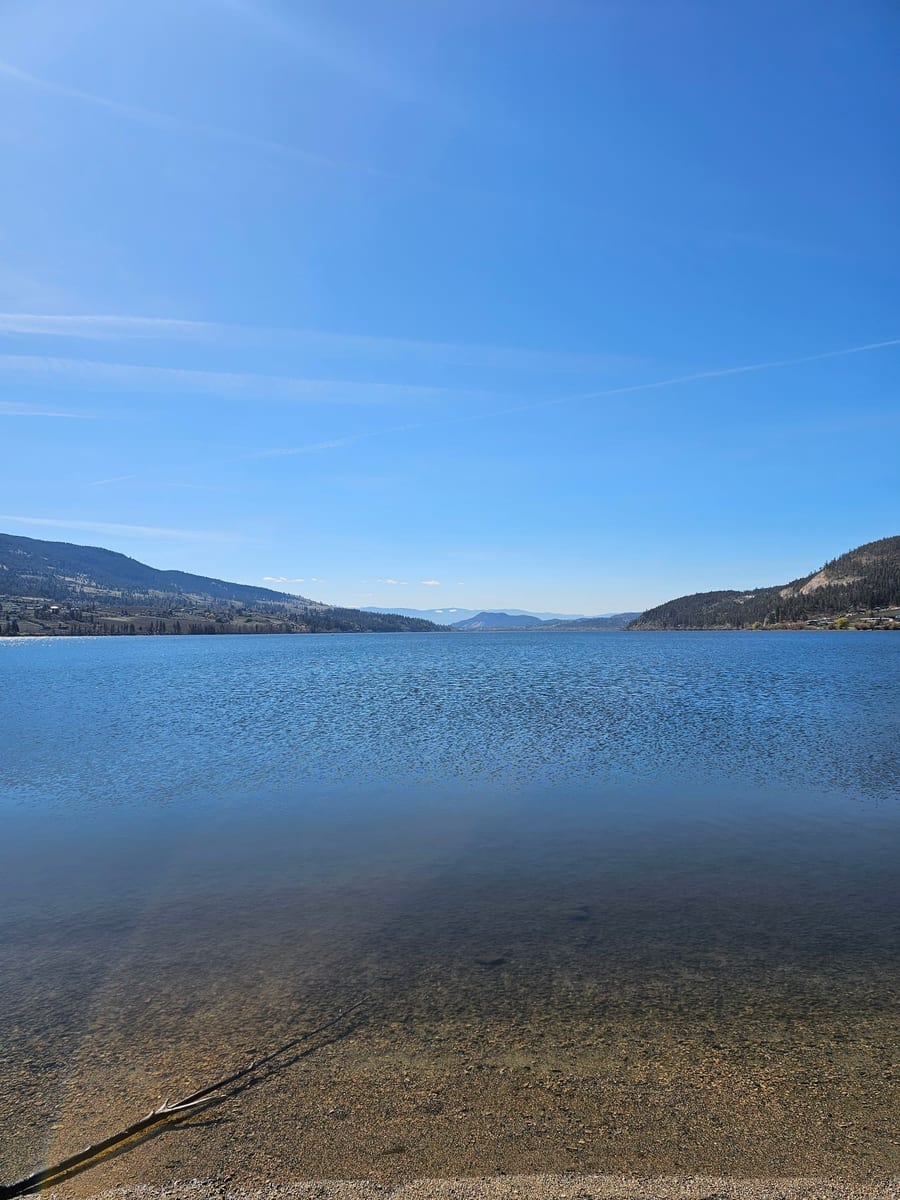 Wood Lake from the beach in front of Lu Lou's, calm water and mountains across