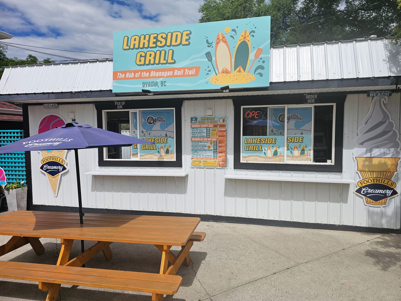 The outside of Lu Lou's Lakeside Grill in Oyama, BC, the order window and patio with picnic tables, right on the Wood Lake beach